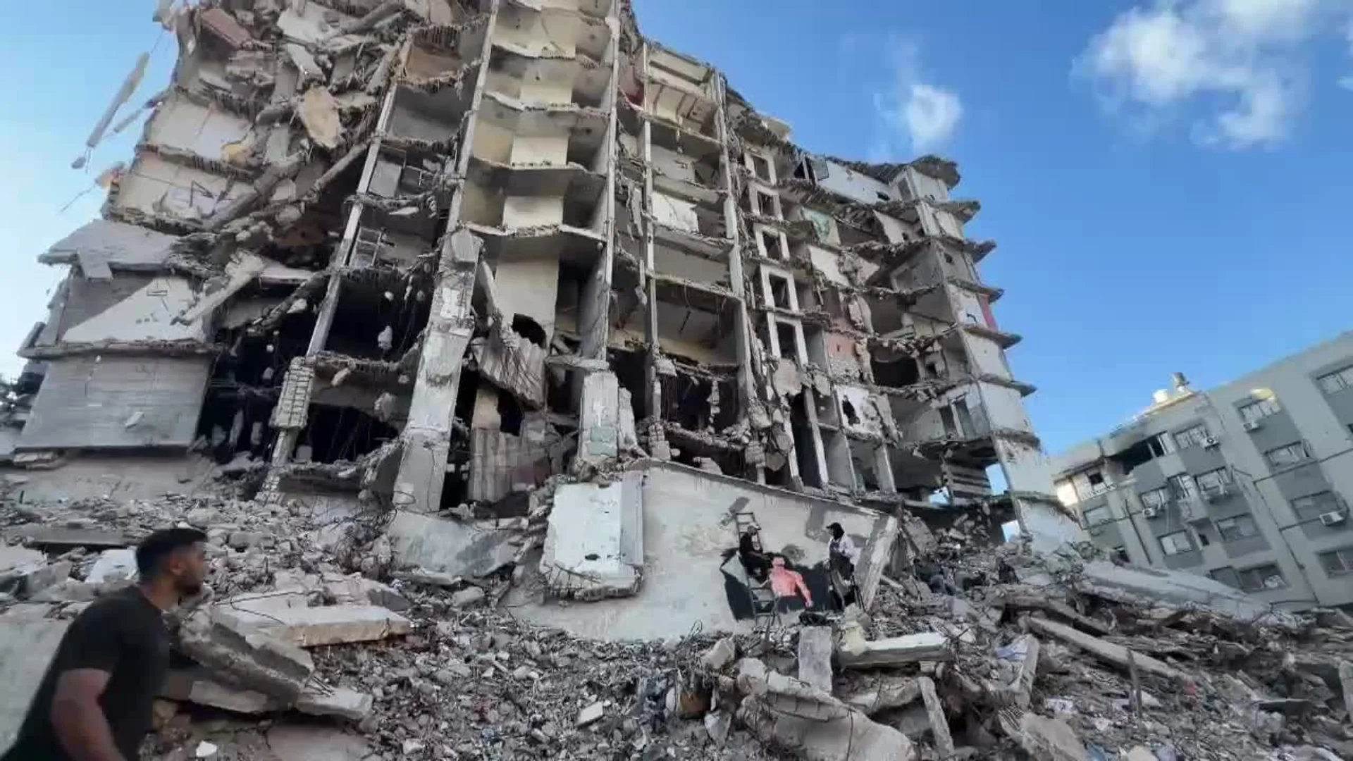 Mural de Dan Reynolds junto a una bandera palestina pintado sobre un edificio destruido en Gaza.